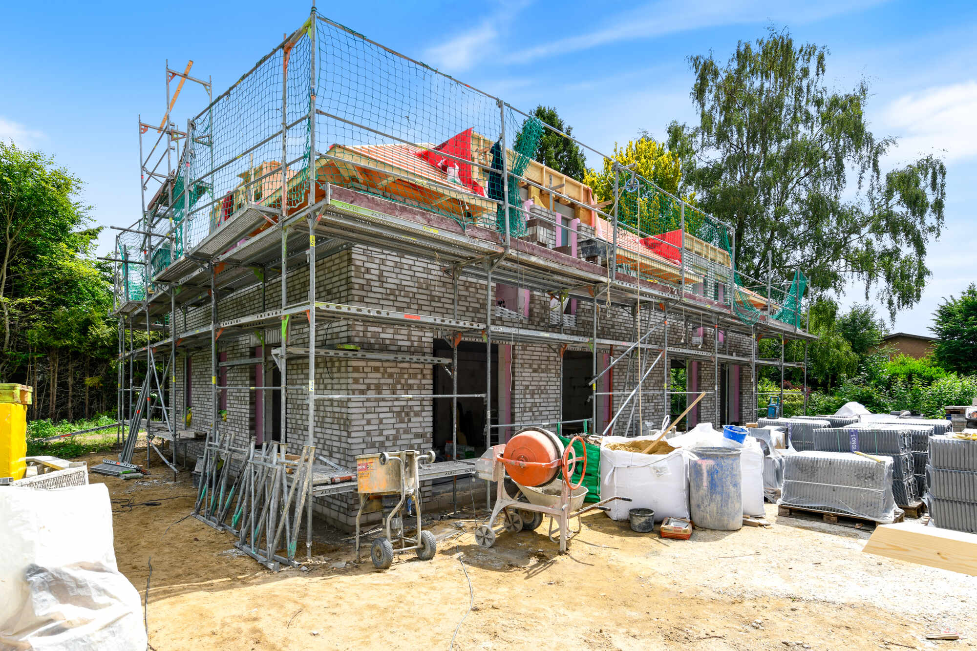 Baufortschritt: Doppelhaushälften mit Klinkerfassade im Rohbau, eingerüstet